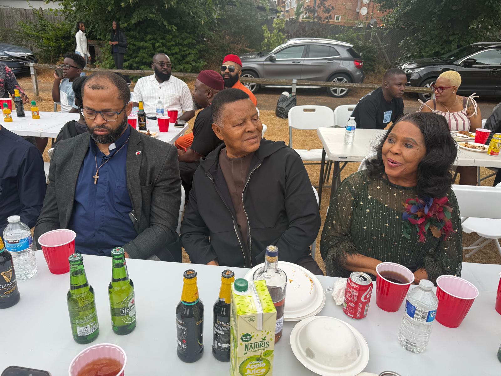 Elders and a clergyman seated together at the AUF community picnic